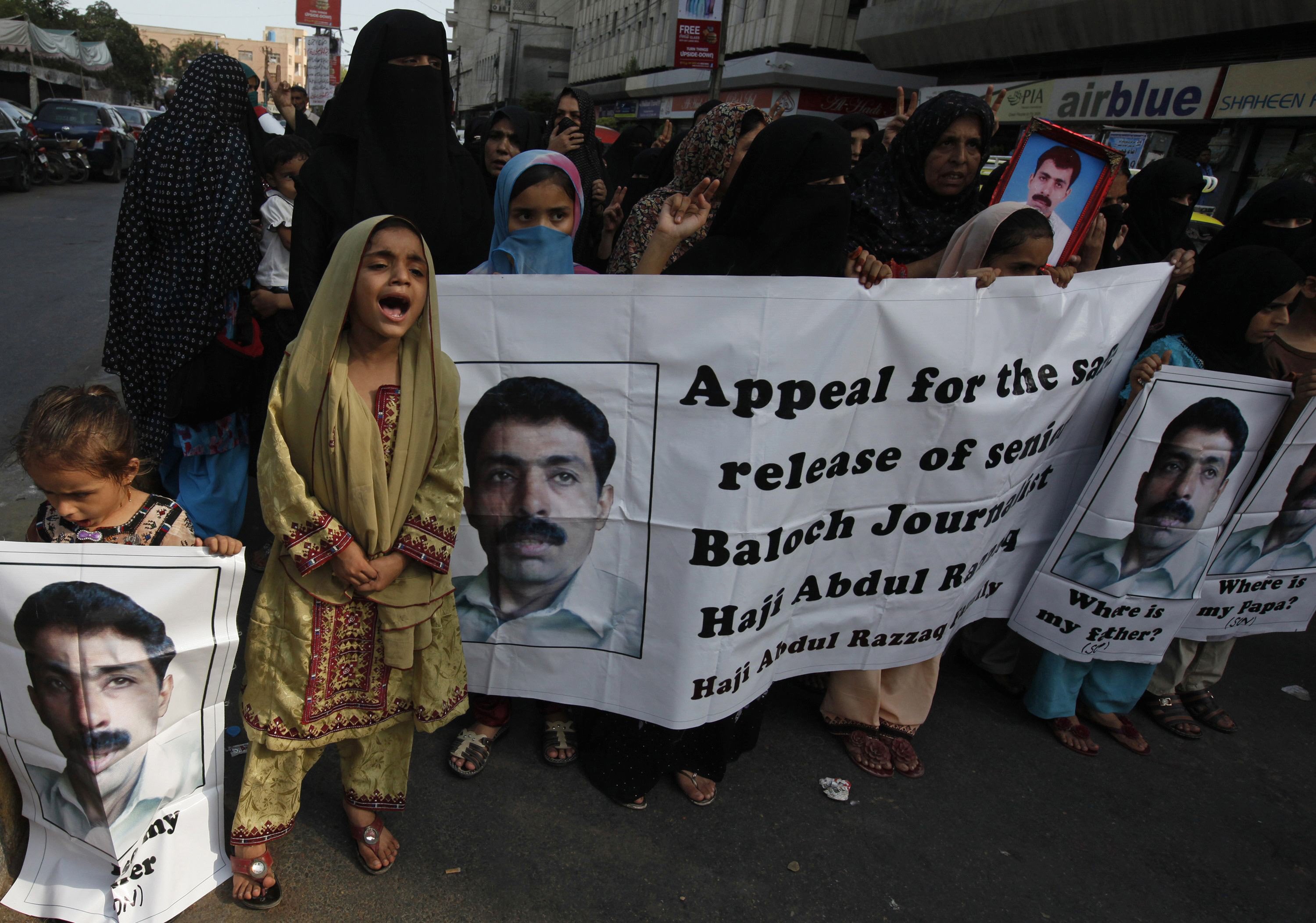 women children and family members of abdul razzaq baloch who had been missing since march hold a banner and posters during a protest outside karachi press club june 4 2013 photo reuters