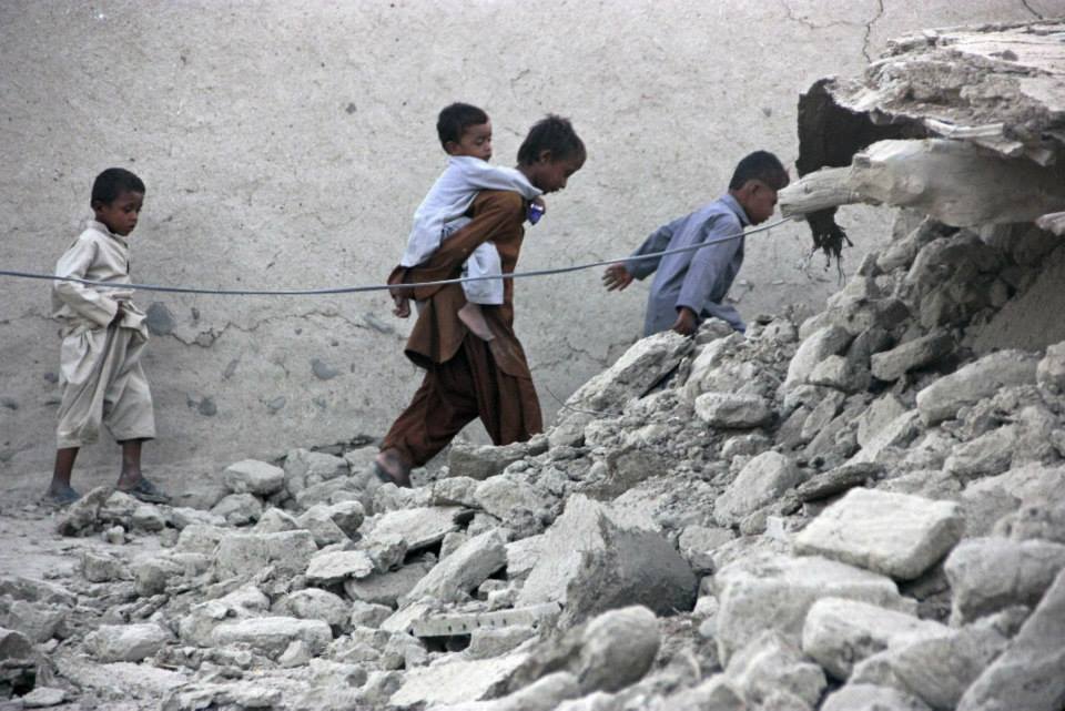 survivors of the balochistan earthquake walk on rubble of a mud house in awaran after it collapsed photo reuters