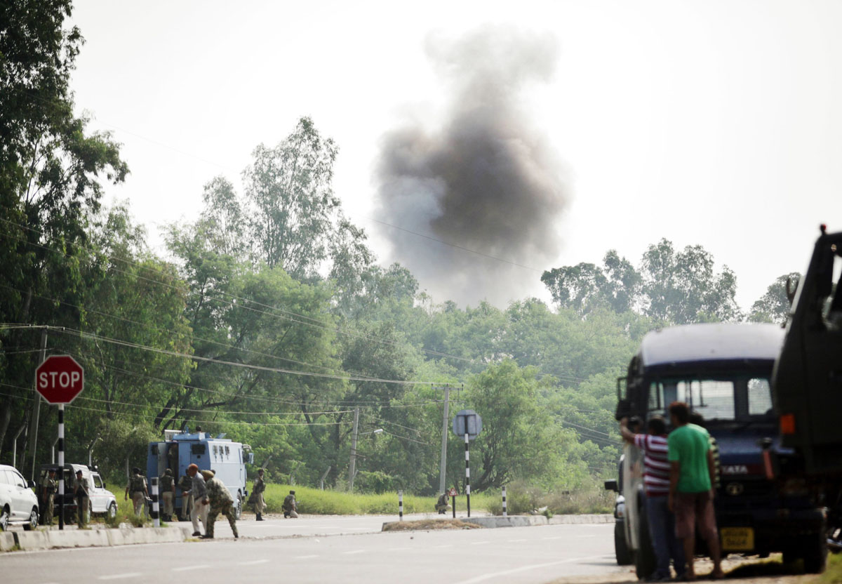 indian police officials civilians and army personnel look on as smoke rises during an attack by militants on an army camp at mesar in samba district photo afp
