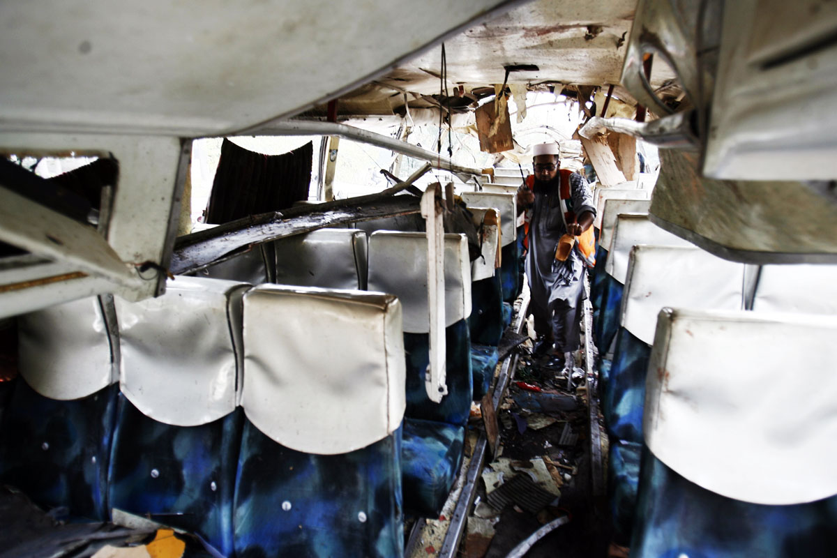 a rescue worker collects evidence from a damaged bus after it was hit by a bomb attack in the outskirts of peshawar september 27 2013 photo reuters