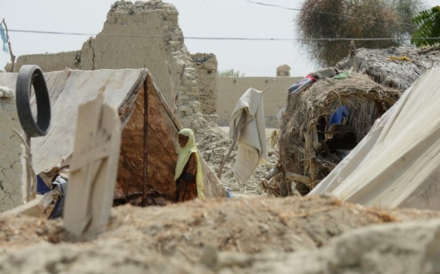 a pakistani earthquake survivor stands in front of her makeshift camp in the devastated district of awaran on september 25 2013 photo afp