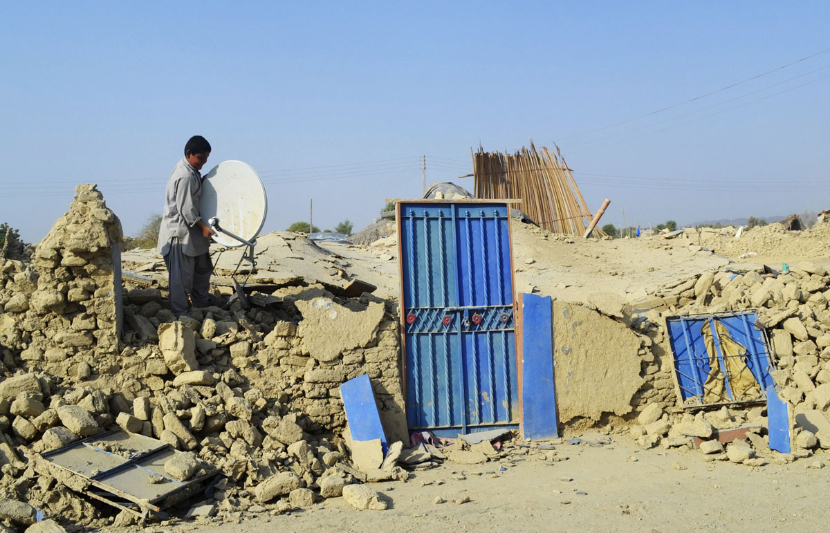 a survivor of an earthquake collects a satellite dish from the rubble of a mud house after it collapsed following the quake at dhallbedi peernder village in awaran district photo reuters