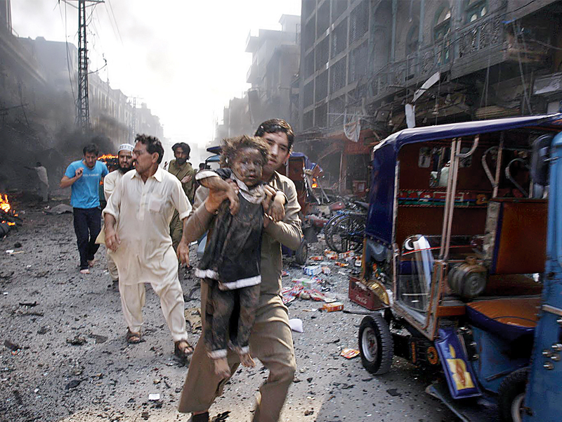 a man carries an injured child away from the site of the blast in qissa khawani bazaar photo inp