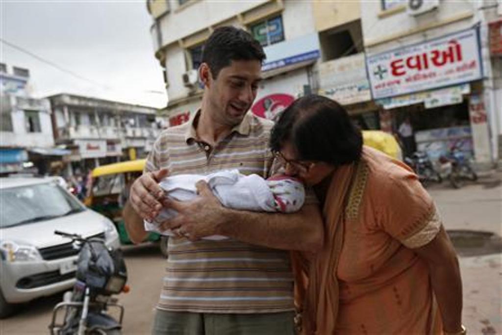 daniele fabbricatore 39 holds his week old daughter gabriella who is kissed by her maternal grandmother vanita patel outside the akanksha ivf centre in anand town about 70km south of the western indian city of ahmedabad august 26 2013 photo reuters