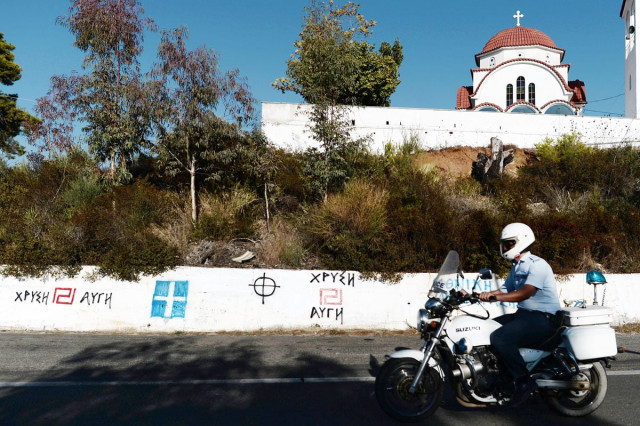 a policeman rides his motorcycle in front of golden dawn and nationalist graffities on a highway in the pelloponese peninsula photo afp a policeman rides his motorcycle in front of golden dawn and nationalist graffities on a highway in the pelloponese peninsula photo afp
