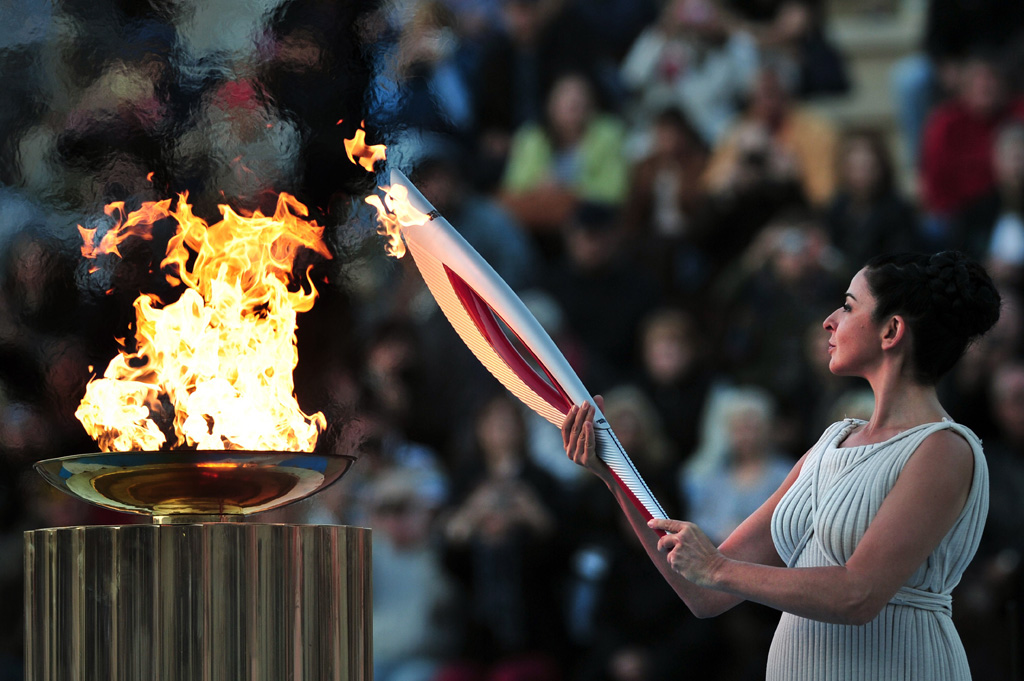 actress ino menegaki playing a high priestess lights a torch from a cauldron on october 5 2013 during the handover ceremony of the olympic flame for the xxii winter olympic games sochi 2014 at the panathenaic stadium in athens photo afp