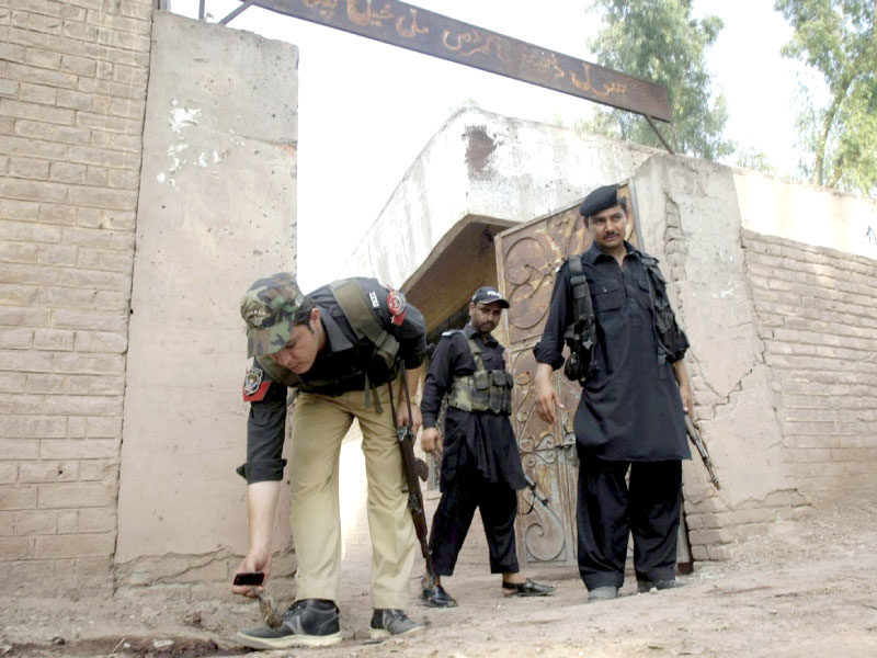 policeman inspects the blast site after a bomb attack outside a dispensary in the outskirts of peshawar photo inp