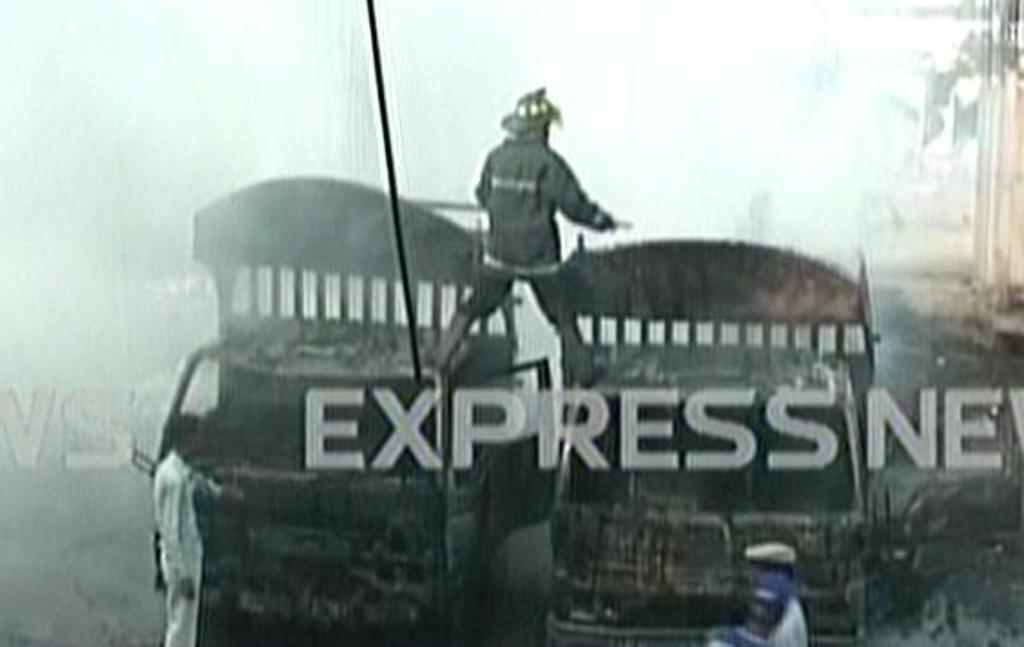 screengrab of a fireman standing on top of two destroyed trucks