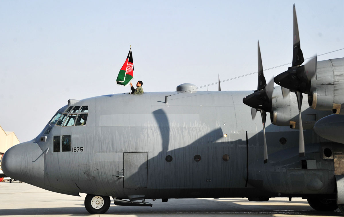 a member of the afghan air force raises the national flag on top of a c 130 transport aircraft at kabul international airport on october 9 2013 photo afp