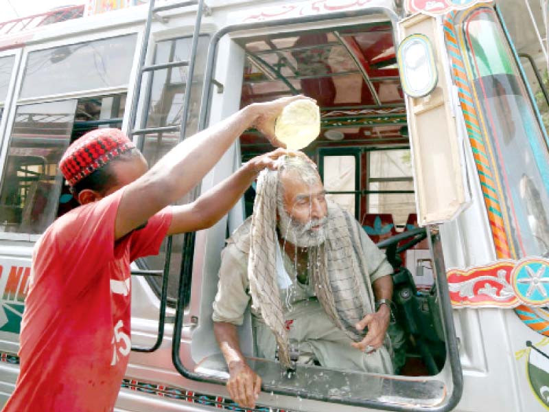 a volunteer of eidhi foundation pours water on the head of a bus driver to prevent him from suffering heatstroke on a road in karachi on monday photo ppi