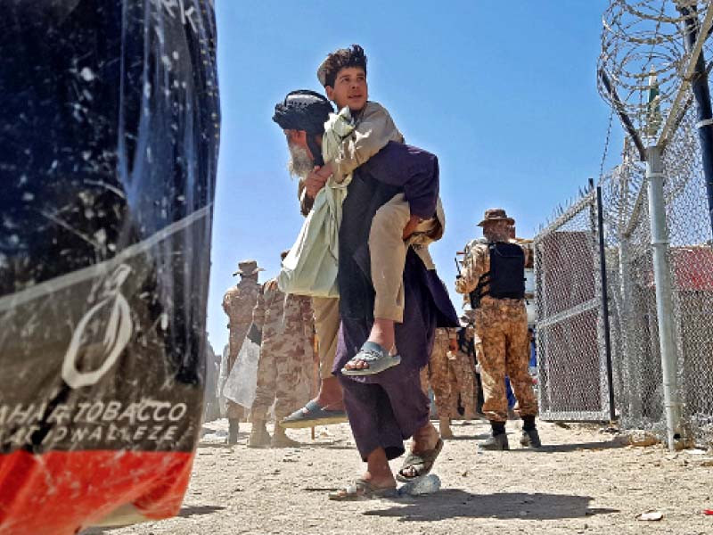 an afghan national carries his son at the pak afghan border crossing point in chaman photo afp