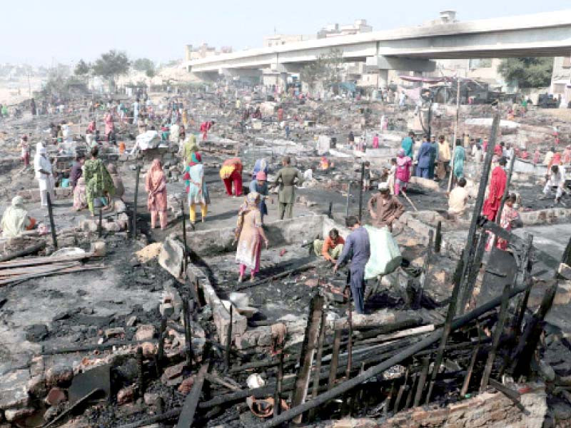 residents of shanties search for their belongings after a huge fire destroyed their makeshift homes under teen hatti bridge near lyari expressway on saturday photo ppi