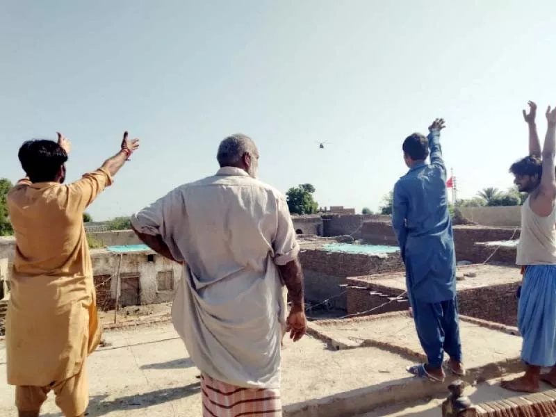 villagers taking shelter on the rooftop of a house of a flood hit village wave to a helicopter for relief supplies photo express villagers taking shelter on the rooftop of a house of a flood hit village wave to a helicopter for relief supplies photo express