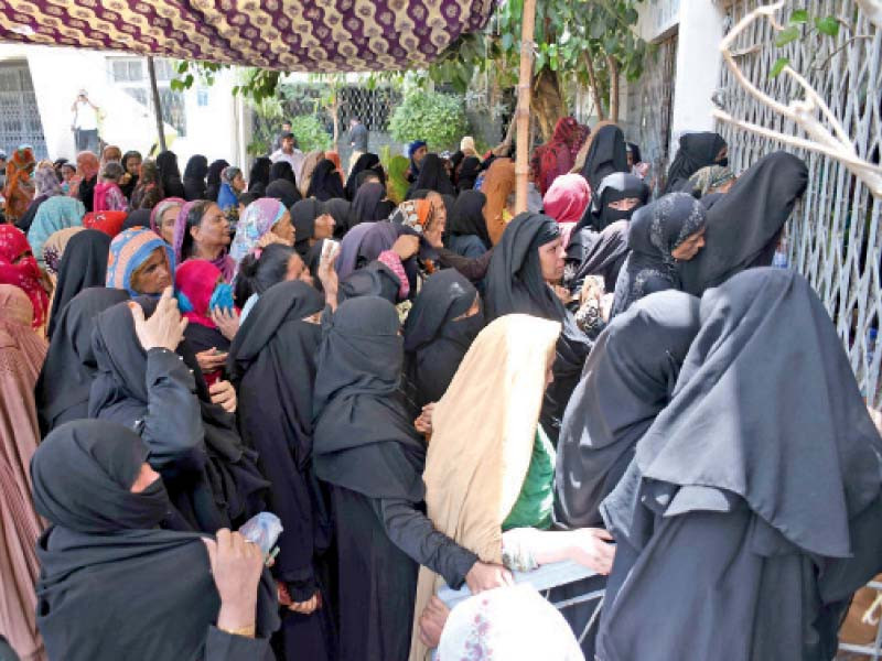 women wait outside the kpt govt secondary school to receive stipend under the benazir income support programme on monday a stampede occurred later at the site when the women rushed in on the opening of the gate photo online
