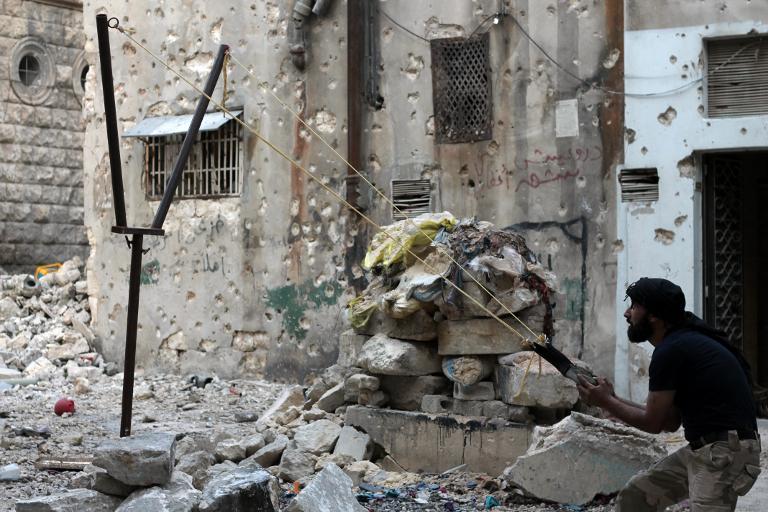 an opposition fighter aims with a catapult towards regime forces in the northern embattled syrian city of aleppo photo afp