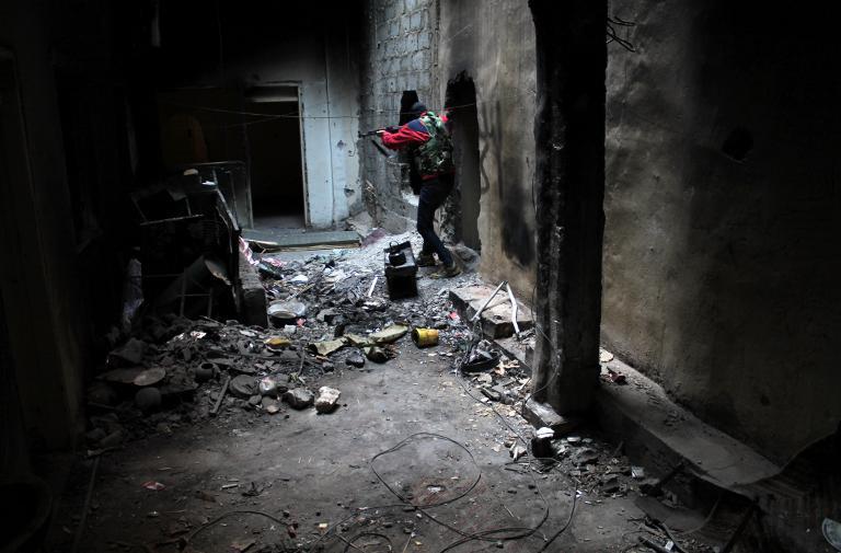 an opposition fighter patrols through an abandoned building in the jubaila neighbourhood of syria 039 s northeastern city of deir ezzor photo afp