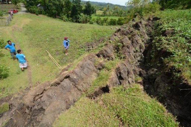 this photo taken on october 22 2013 shows residents standing next to a huge crack creating a rock wall in the village of anonang inabanga town bohol province brought about by the 7 2 magnitude quake which hit the province october 15 photo afp this photo taken on october 22 2013 shows residents standing next to a huge crack creating a rock wall in the village of anonang inabanga town bohol province brought about by the 7 2 magnitude quake which hit the province october 15 photo afp