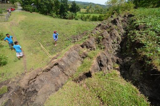 this photo taken on october 22 2013 shows residents standing next to a huge crack creating a rock wall in the village of anonang inabanga town bohol province brought about by the 7 2 magnitude quake which hit the province october 15 photo afp