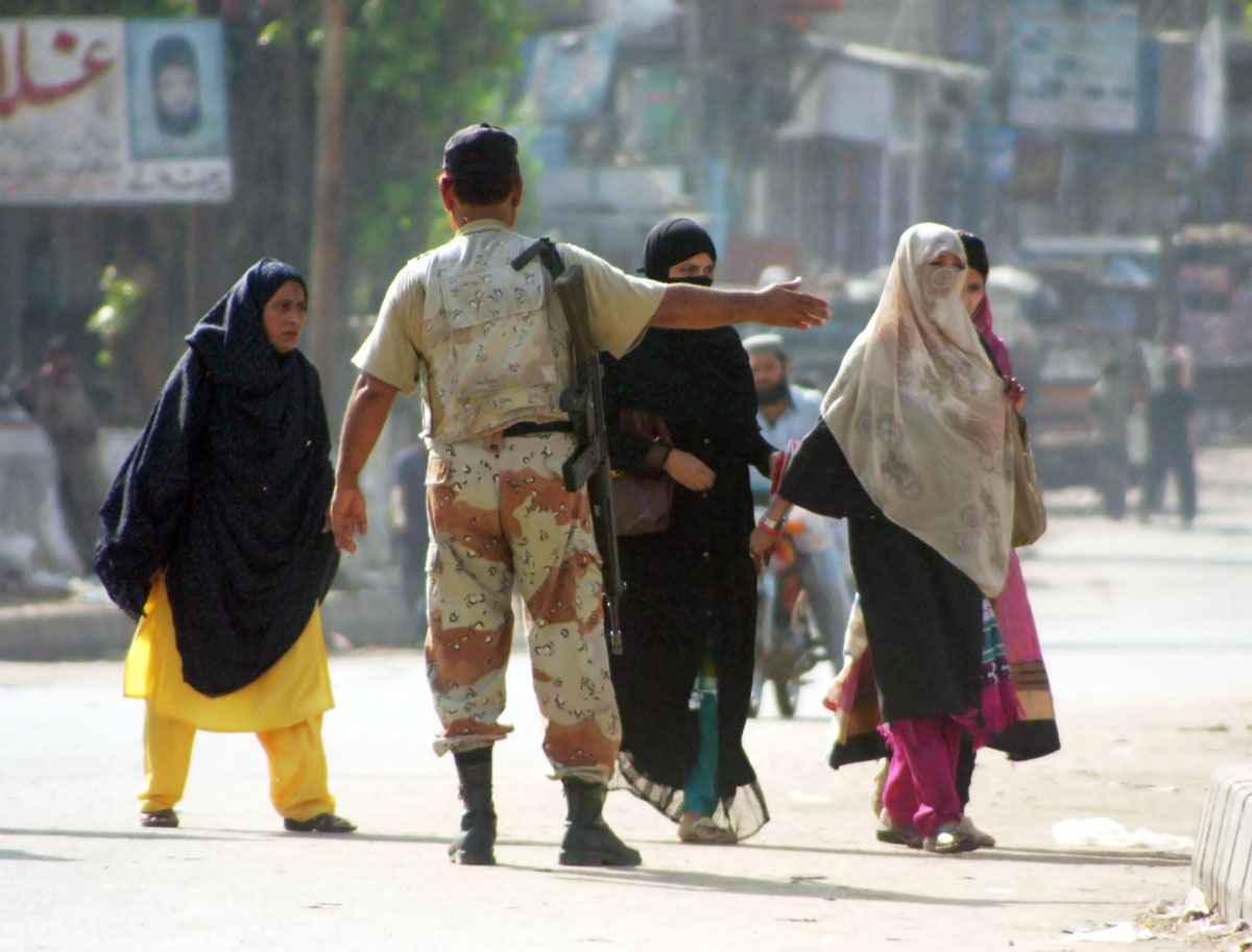 a ranger directs women in lyari on tuesday during a lockdown as part of a clean up operation photo mohammad azeem exress