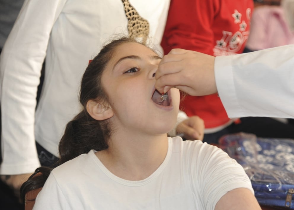 a syrian health worker administers polio vaccination to a girl at a school in damascus in this file photo taken by syria 039 s national news agency sana on october 20 2013 photo reuters