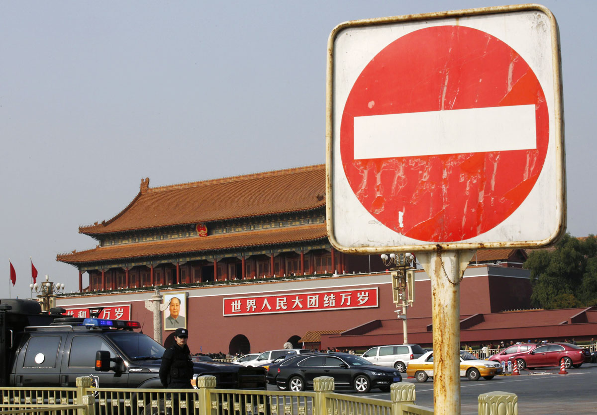 a sign is seen next to a policeman of the special weapons and tactics swat team standing guard in front of the giant portrait of chinese late chairman mao zedong on tiananmen square in beijing october 30 2013 photo reuters