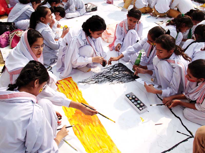 young school girls paint together on a canvass at the children s literature festival on thursday photo shafiq malik express