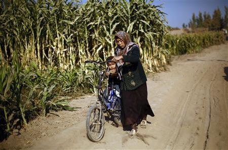 an ethnic uighur woman pushes a bicycle with her son on it along a dirt road in turpan xinjiang province photo reuters