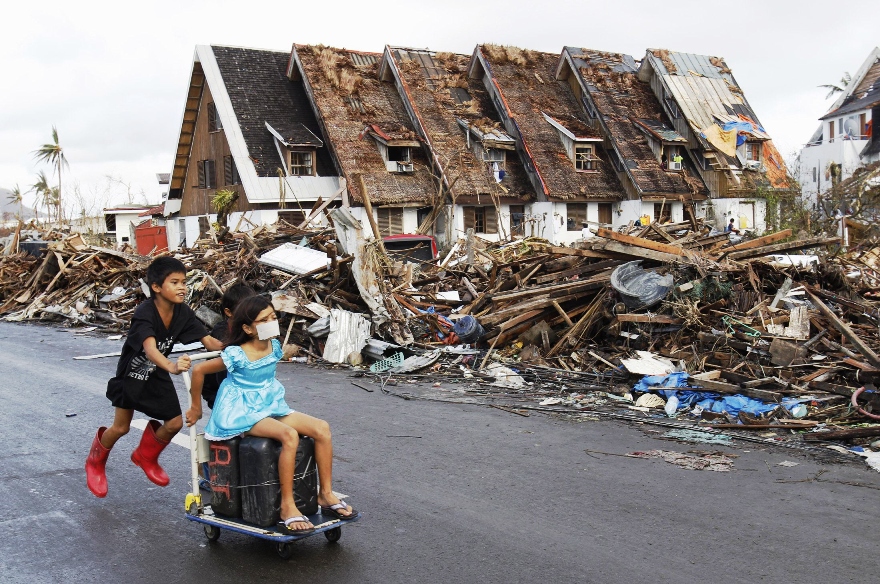 residents pass houses devastated by typhoon haiyan in tacloban city central philippines november 13 2013 photo reuters