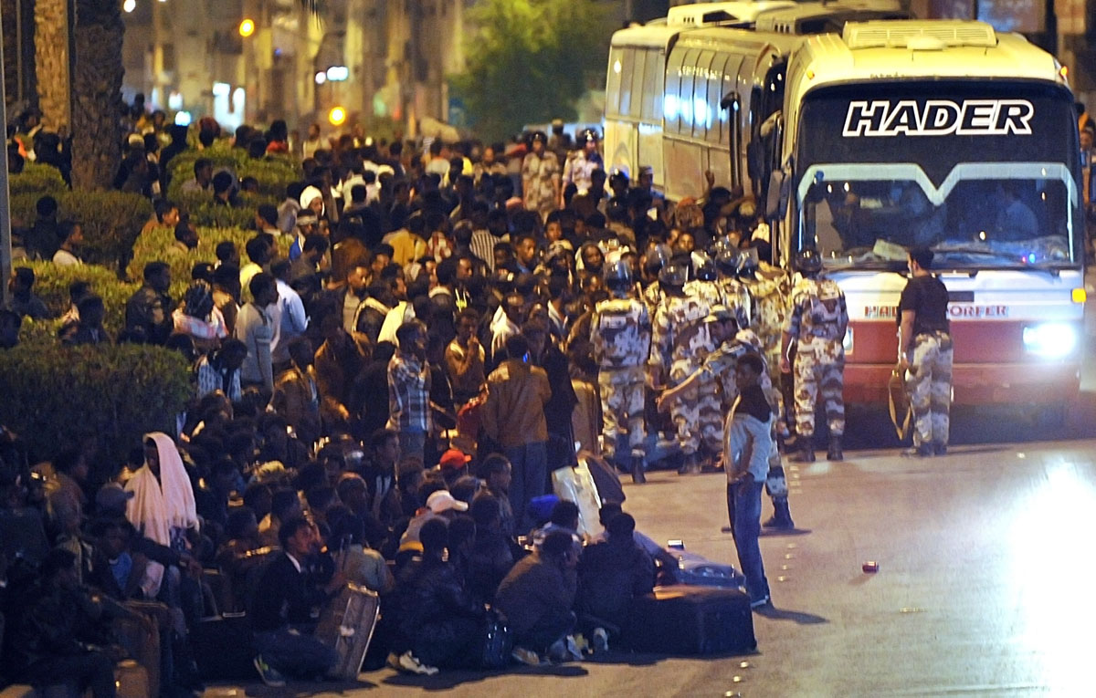 illegal migrants wait with their belongings under police watch to be transferred by police buses on november 13 2013 to a center in the capital riyadh ahead of their deportation photo afp