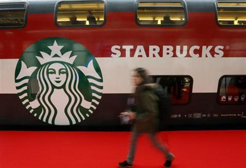 a woman walks past a starbucks logo painted on a railway coach at the main train station in zurich photo reuters