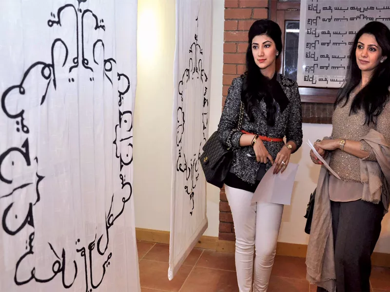 a segment of the exhibition consists of with plain white blinds with writings in urdu scrolled around the edges photos express a segment of the exhibition consists of with plain white blinds with writings in urdu scrolled around the edges photos express