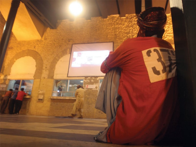 a porter at karachi cantonment railway station watches a series of movies on karachi at a mobile cinema set up inside the premises on sunday night photo athar khan express a porter at karachi cantonment railway station watches a series of movies on karachi at a mobile cinema set up inside the premises on sunday night photo athar khan express
