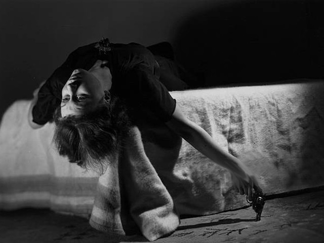 a woman sprawls over a bed holding a gun in her hand as she contemplates suicide photo getty