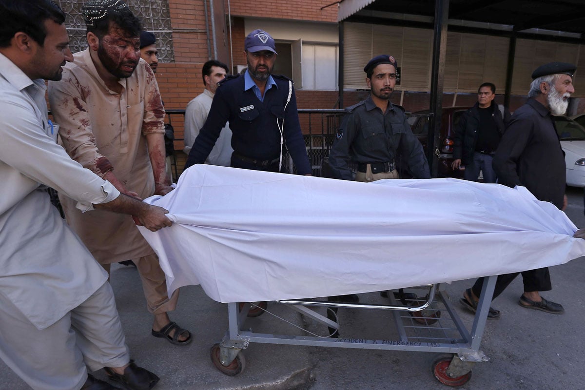 policemen shift the body of a colleague at a hospital after an attack on a polio vaccination team in peshawar on november 30 2013 photo afp