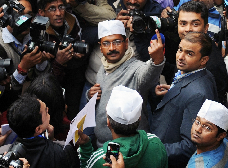 indian aam aadmi party leader arvind kejriwal c gestures with his ink marked finger after casting his vote for the delhi state assembly election in new delhi on december 4 2013 photo afp