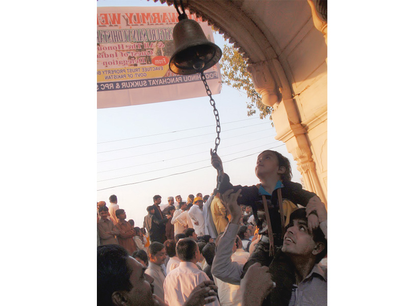 a hindu boy rings a bell at the sadh belo temple in sukkur photo express