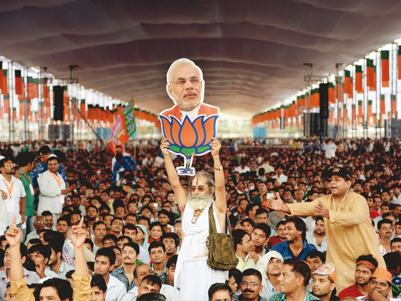 a bjp supporter holds a cutout of narendra modi after the party s state election victory photo afp