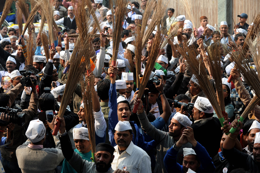 supporters of the indian aam aadmi party common man 039 s party hold brooms the party symbol as they celebrate outside the aap office after their candidate arvind kejriwal won the state assembly election aganist delhi chief minister sheila dikshit in new delhi on december 8 2013 photo afp