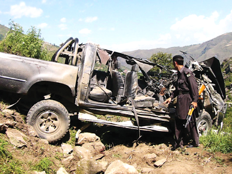 a security personnel stands next to vehicles damaged by a roadside bomb photo online file