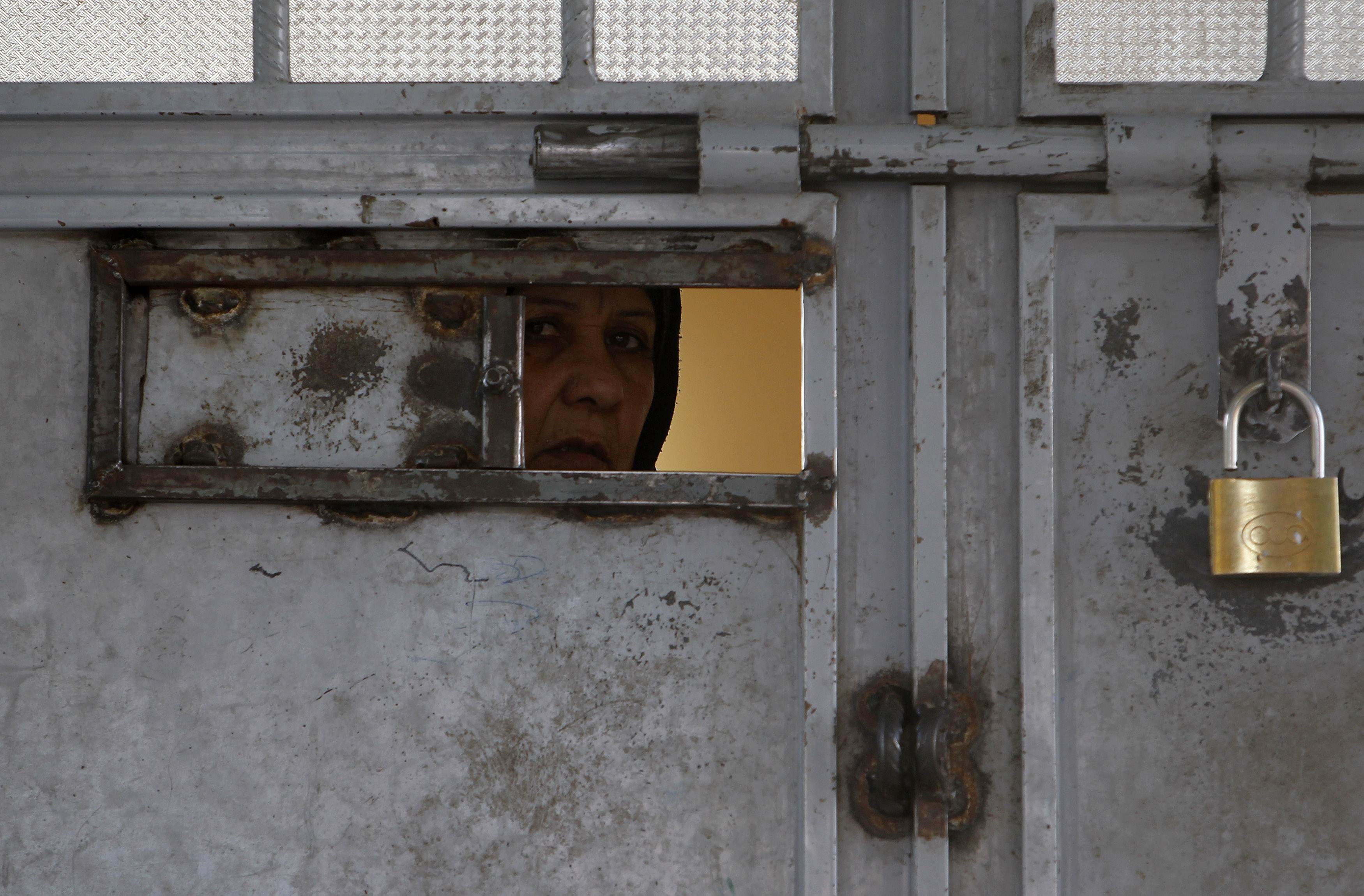 an afghan woman looks out from a viewing panel in a door at herat prison western afghanistan photo reuters