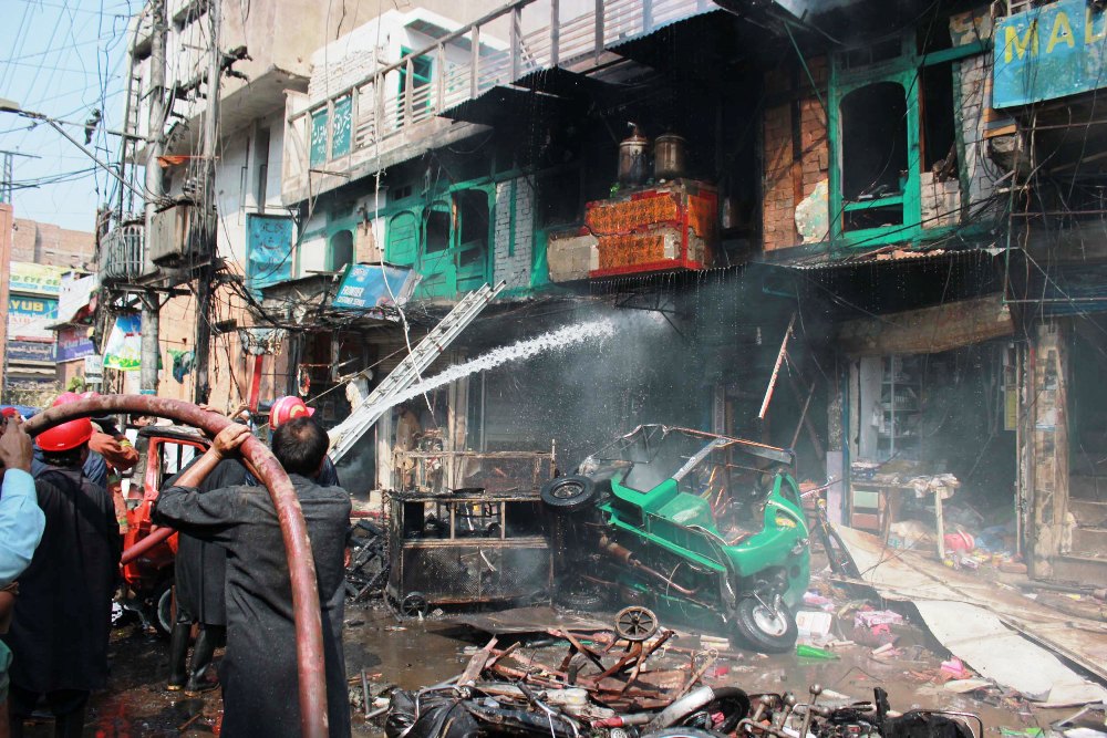 rescue workers trying to extinguish fire that erupted after the explosion in peshawar 039 s qissa khwani area on september 29 2013 photo muhammad iqbal