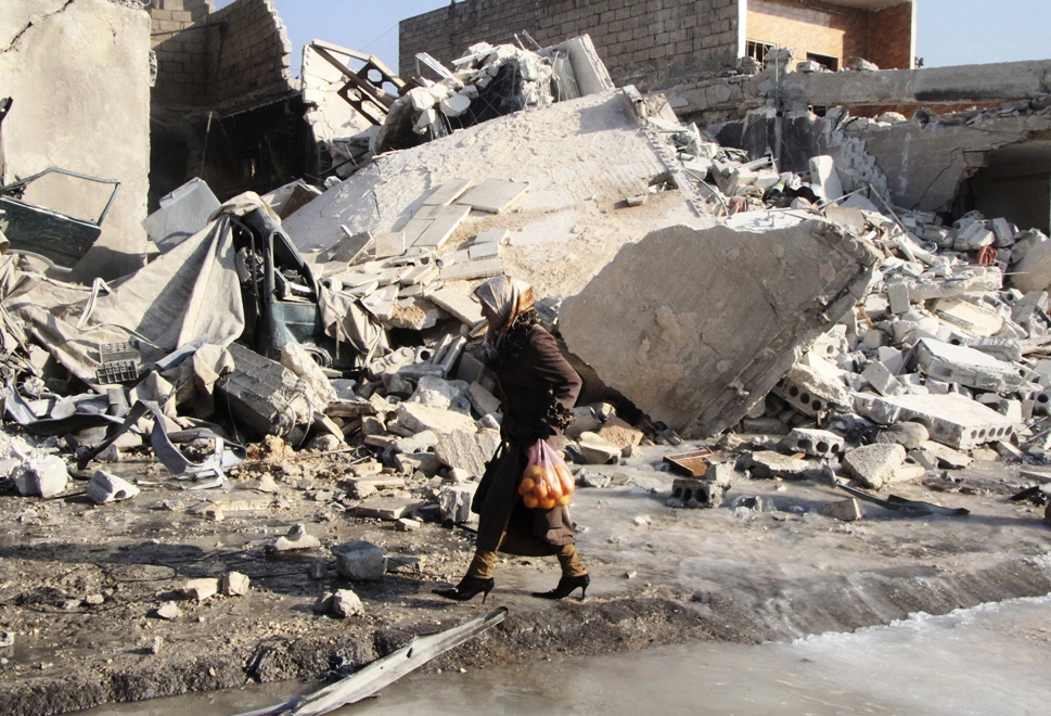 a woman carrying oranges walks past debris at a site damaged by what activists said was an air raid by forces loyal to syrian president bashar al assad at masaken hanano in aleppo december 22 2013 photo reuters