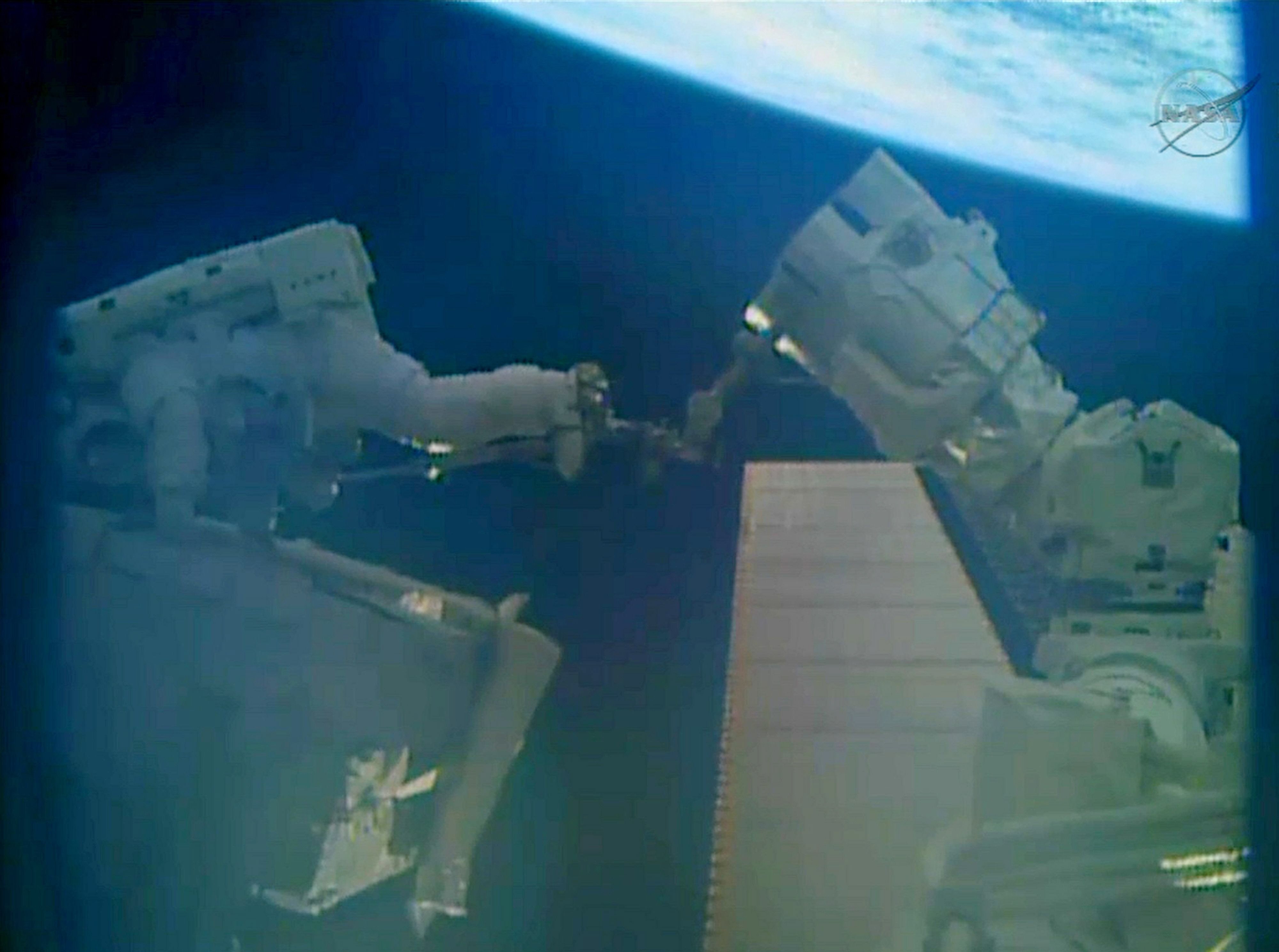 this december 24 2013 nasa tv still image shows astronaut mike hopkins l on the robotic arm holding a spare pump and rick mastracchio slide it into the truss during a spacewalk outside the ineternational space station iss photo afp