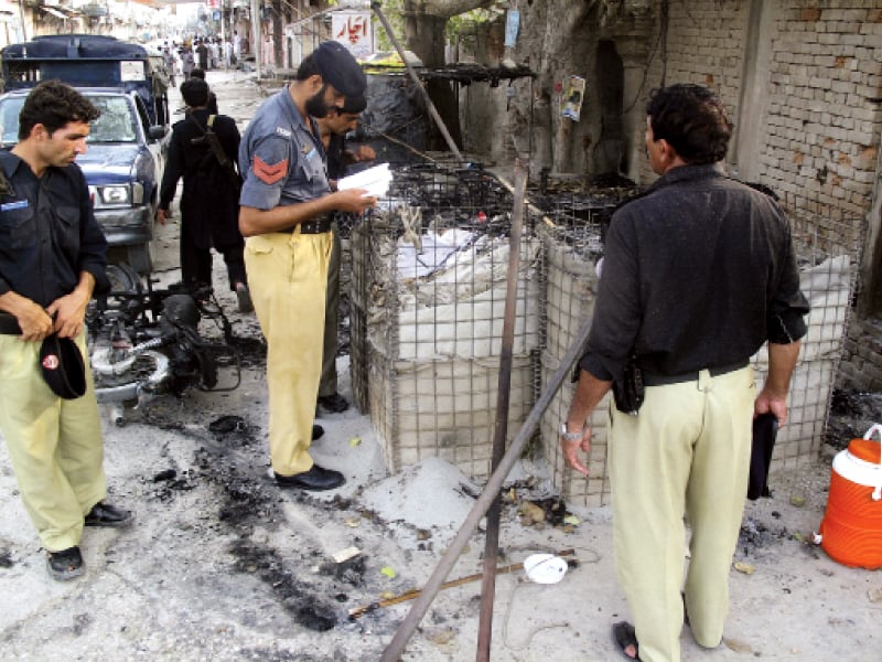 policemen collect evidence outside the site following the brazen attack in di khan photo reuters