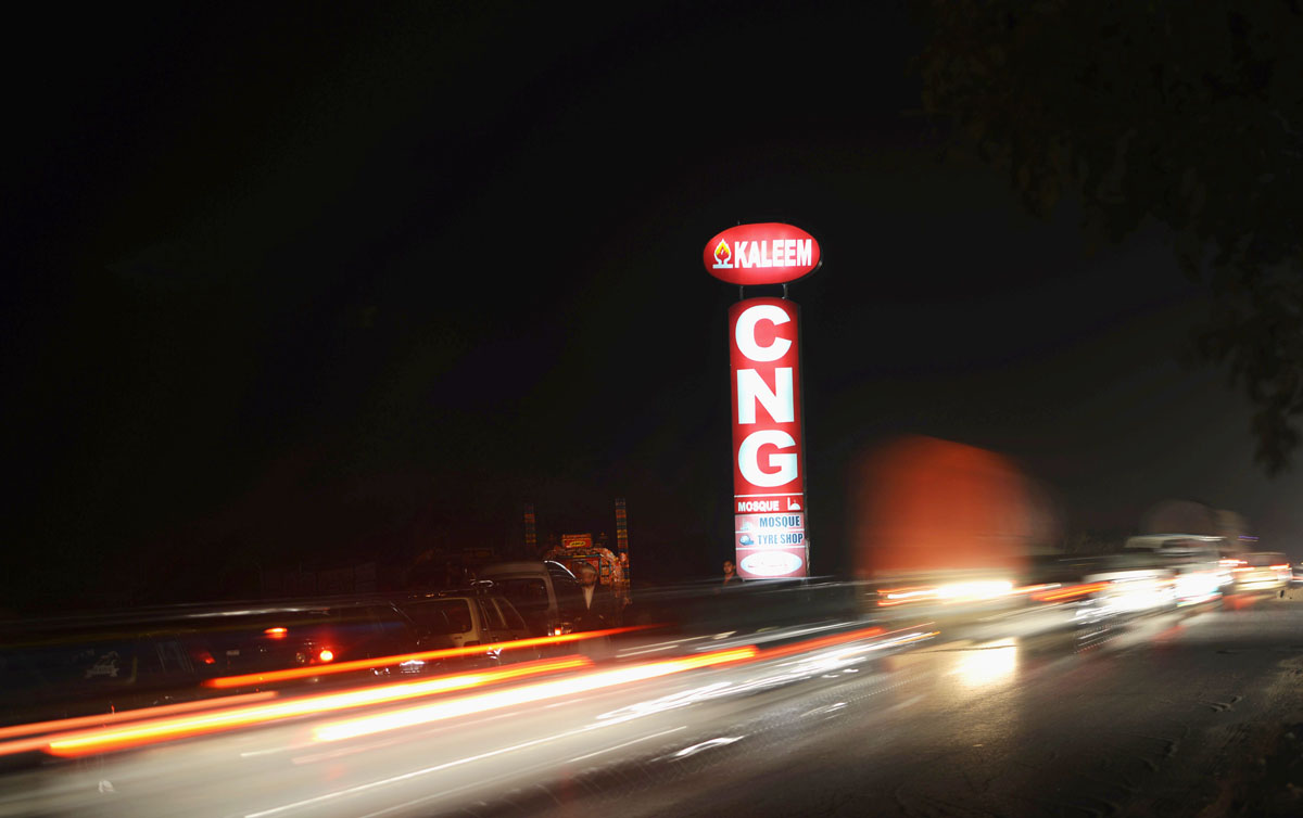 traffic streams past vehicles which are queued outside a filling station in islamabad on december 26 2013 photo afp