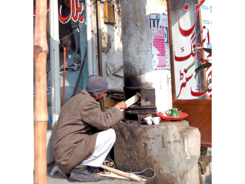 a man using a wood geyser to heat water for a nearby shop photo muhammad javaid express