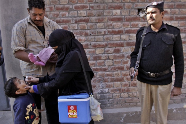 a policeman stands guard as female polio workers give vaccine drops to children photo shafiq malik a policeman stands guard as female polio workers give vaccine drops to children photo shafiq malik