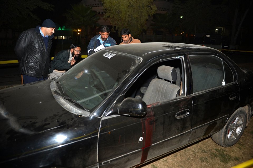 a mourner along with investigators inspects a car after an attack by unknown gunmen on mufti muneer ahmed in islamabad on january 3 photo afp