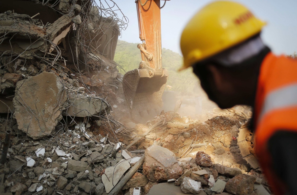 a rescuer looks on as an excavator works at the site of a collapsed building that was under construction in canacona town in the western indian city of goa january 5 2014 photo reuters