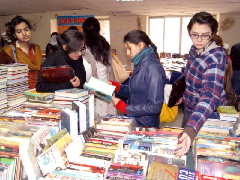 girls looking at books heaped on the tables photo express